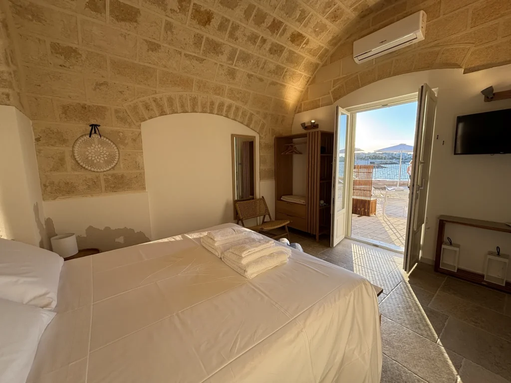 Camera con volta in pietra e portafinestra aperta sulla terrazza vista mare