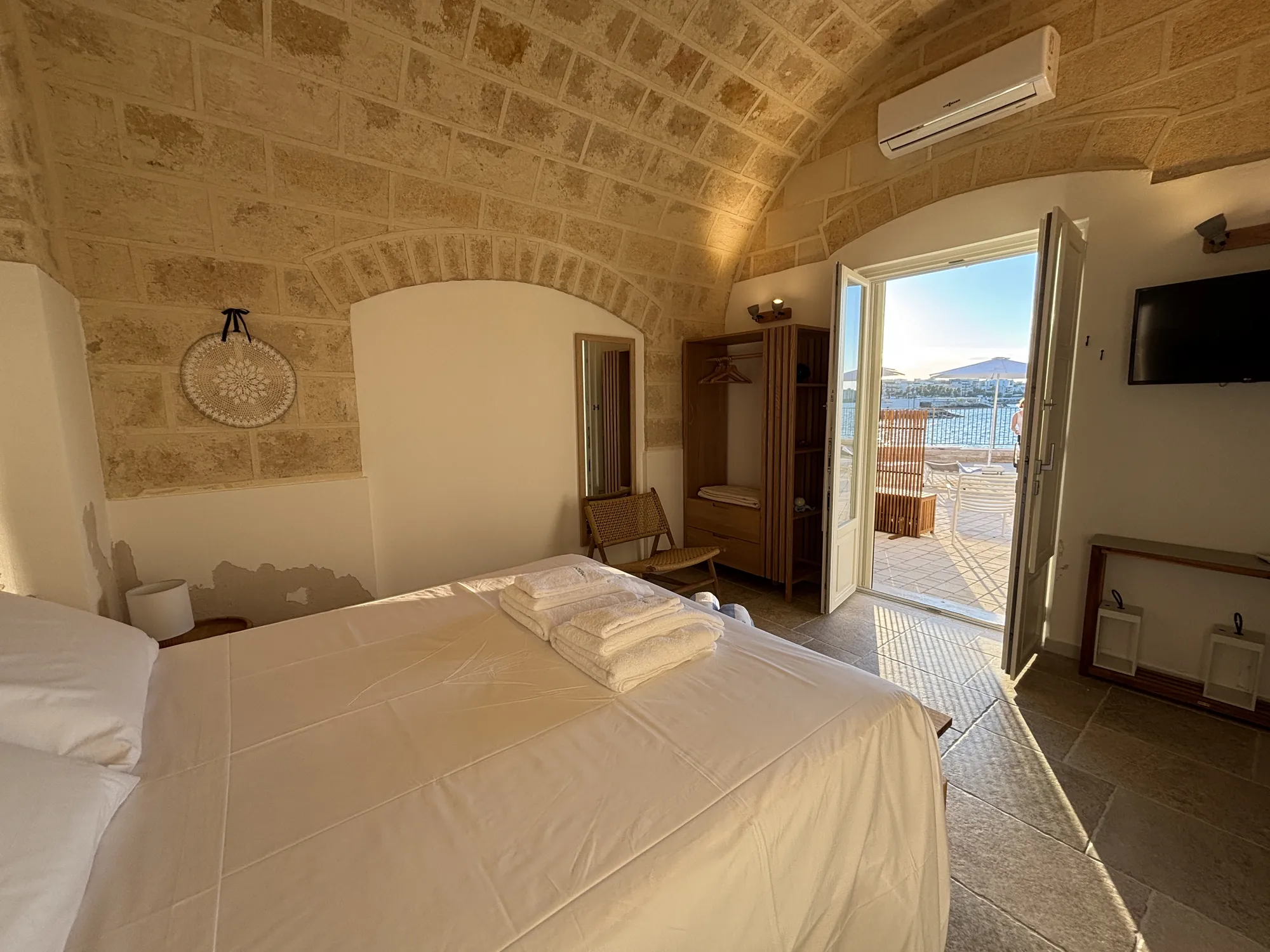 Camera con volta in pietra e portafinestra aperta sulla terrazza vista mare