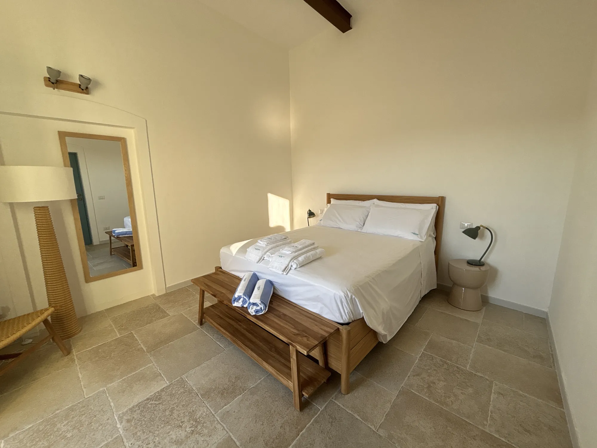 Letto matrimoniale con panca in legno, specchio e lampada da terra
