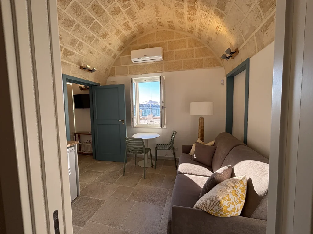 Soggiorno con divano letto, tavolino tondo e finestra sul mare