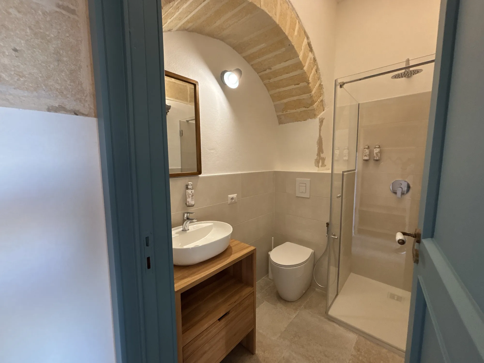 Bagno privato con doccia sotto l'arco in pietra