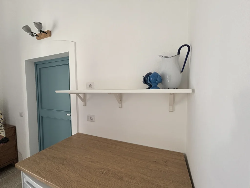 Angolo cottura con piano in legno e mensola con brocca e pumo