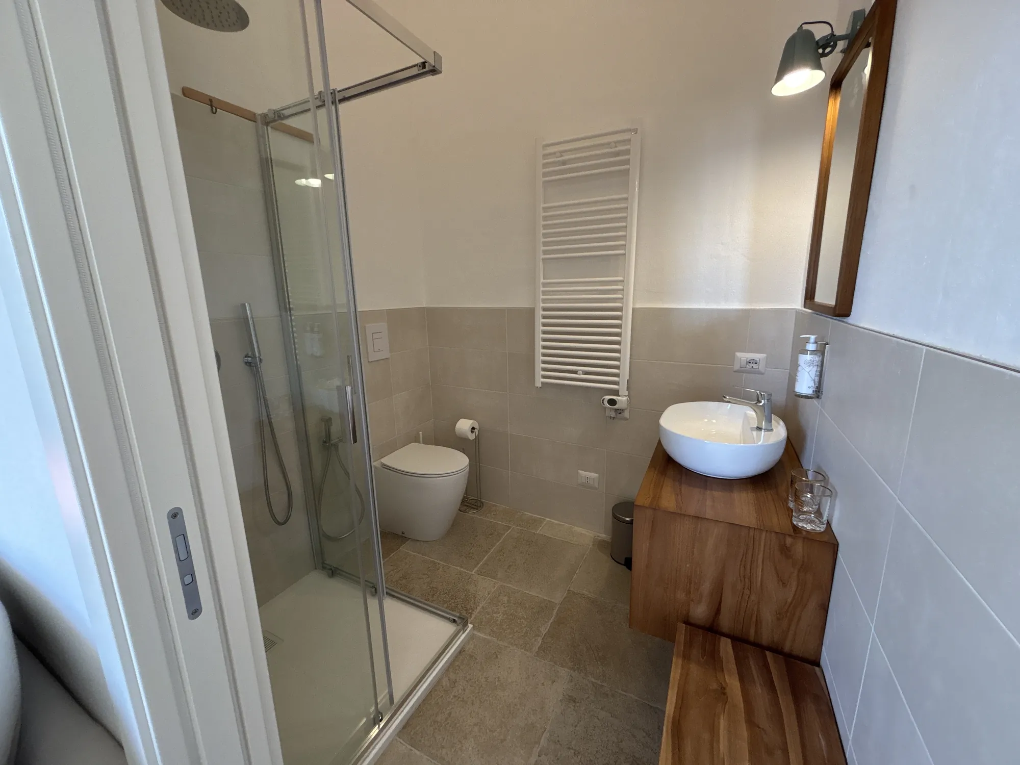 Bagno privato con doccia, lavabo d'appoggio e mobile in legno