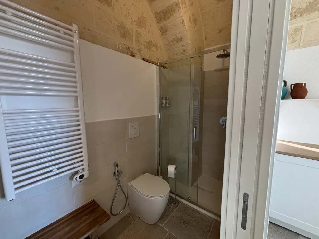 Bagno privato con doccia in vetro e volta in pietra