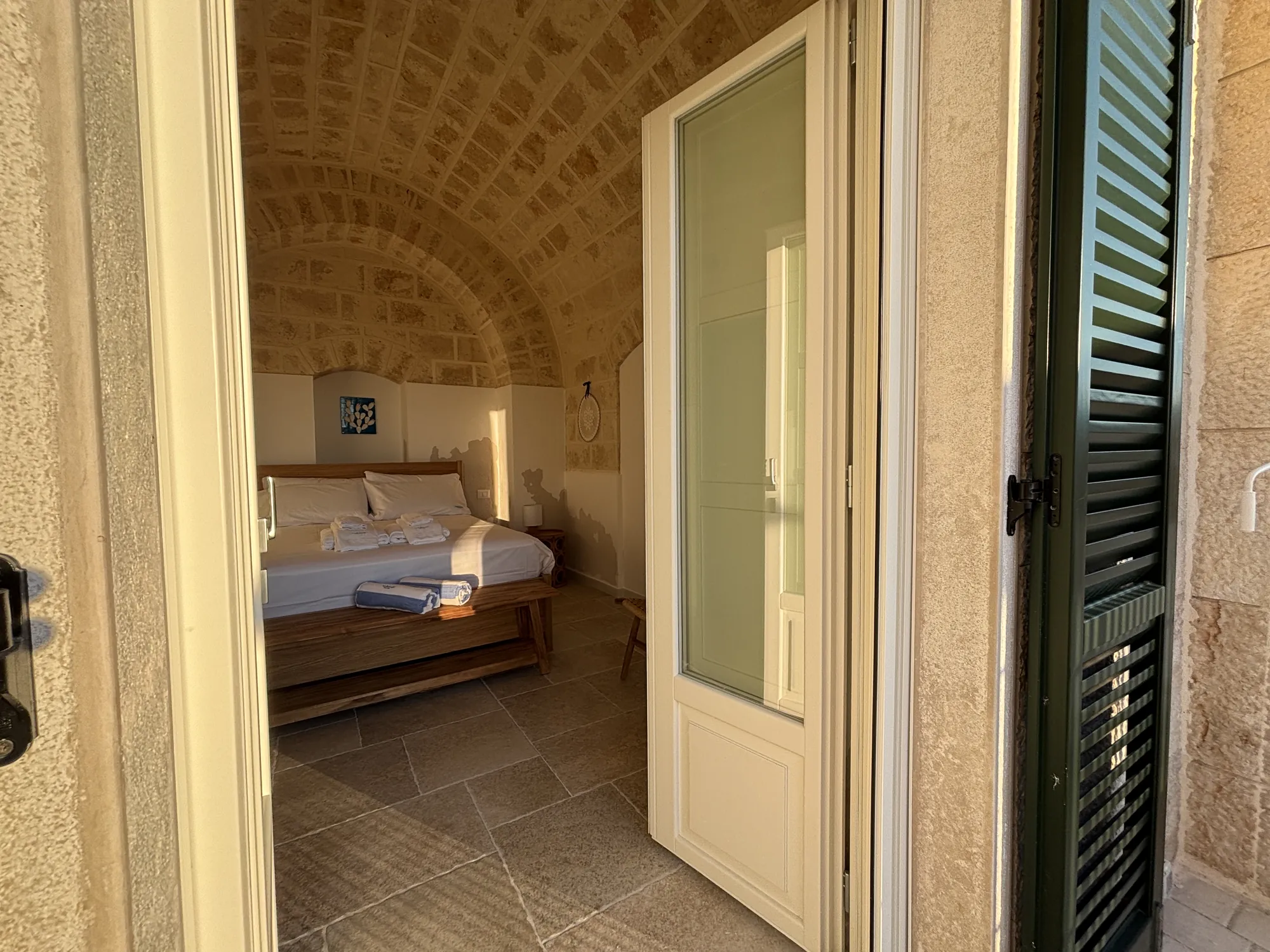 La camera vista dalla terrazza, oltre la portafinestra con le persiane verdi
