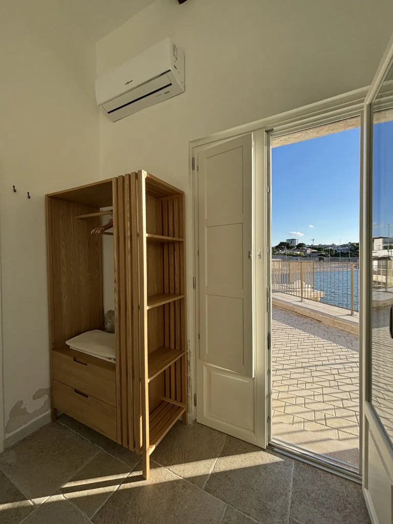 Armadio in legno e portafinestra aperta sulla terrazza vista mare