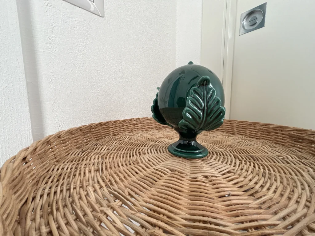 Pumo pugliese in ceramica verde su un tavolino in rattan