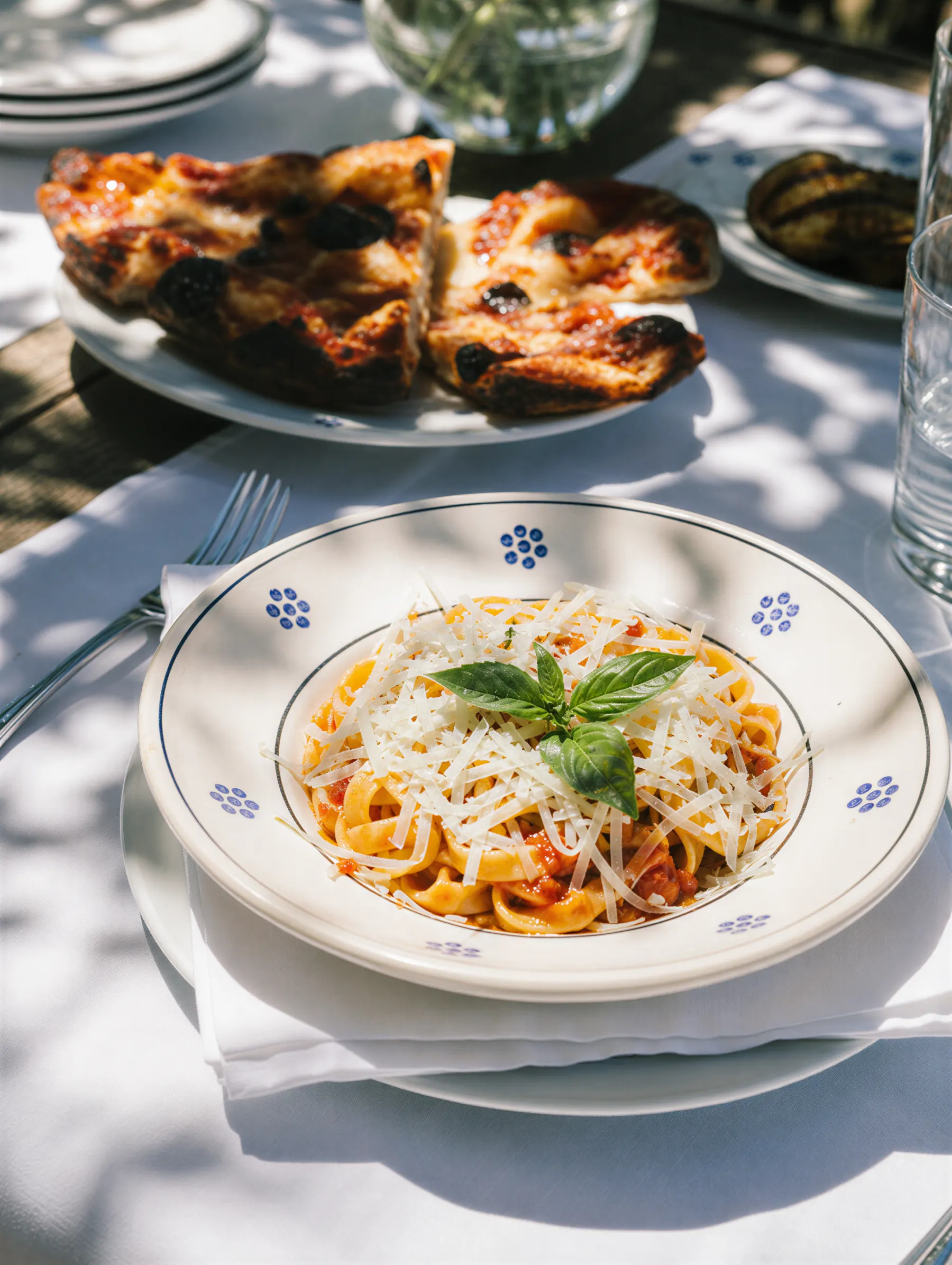 Pasta al pomodoro con basilico e focaccia pugliese su una tavola apparecchiata all'aperto